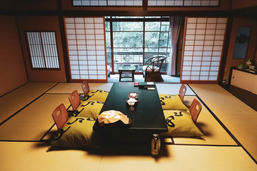 Guest room at Arai Ryokan in Shuzenji: tatami, a low lacquer table, and a balcony opening onto forest