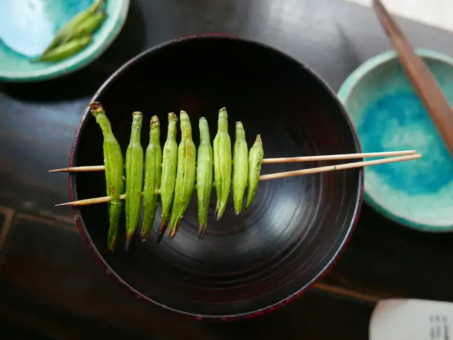 Grilled okra skewer on a Japanese lacquer bowl with chopsticks — dining etiquette at Japanese restaurants