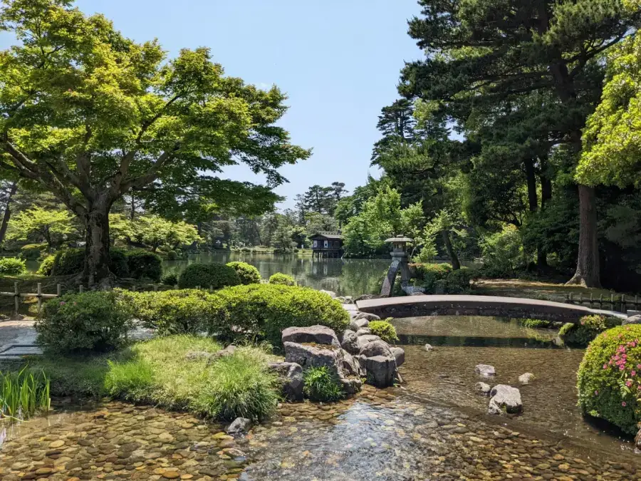 Kenroku-en garden in Kanazawa in summer — stone lanterns, a tranquil pond and lush green trees
