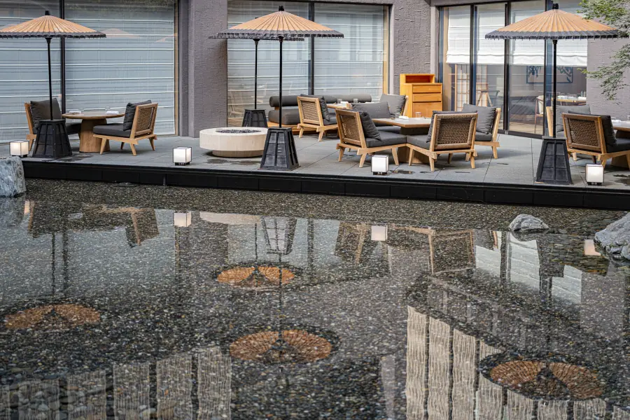 Courtyard terrace of a luxury hotel in Kyoto with paper umbrellas reflected in a pebbled water garden