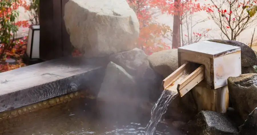 Luxury ryokan onsen in Japan — private hot spring bath with traditional wooden architecture