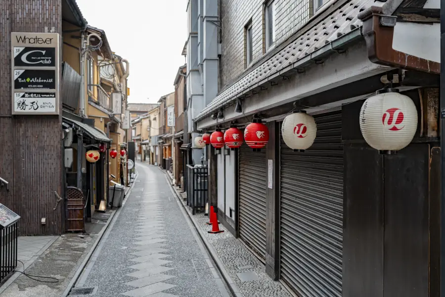 The narrow Pontocho alley in downtown Kyoto at dawn, empty, with paper lanterns along the facades