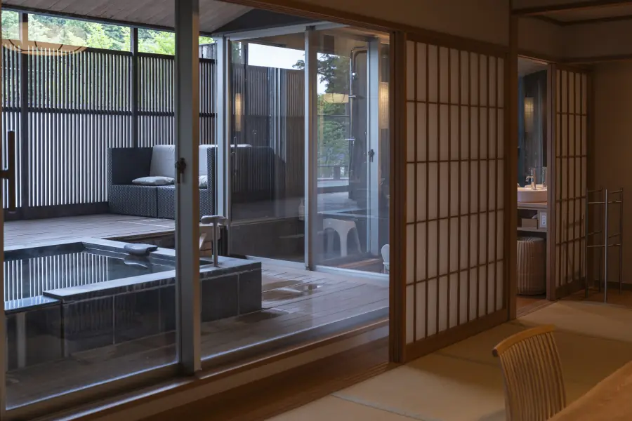 Private open-air onsen bath on the terrace of a ryokan suite in Hakone, seen from the tatami room