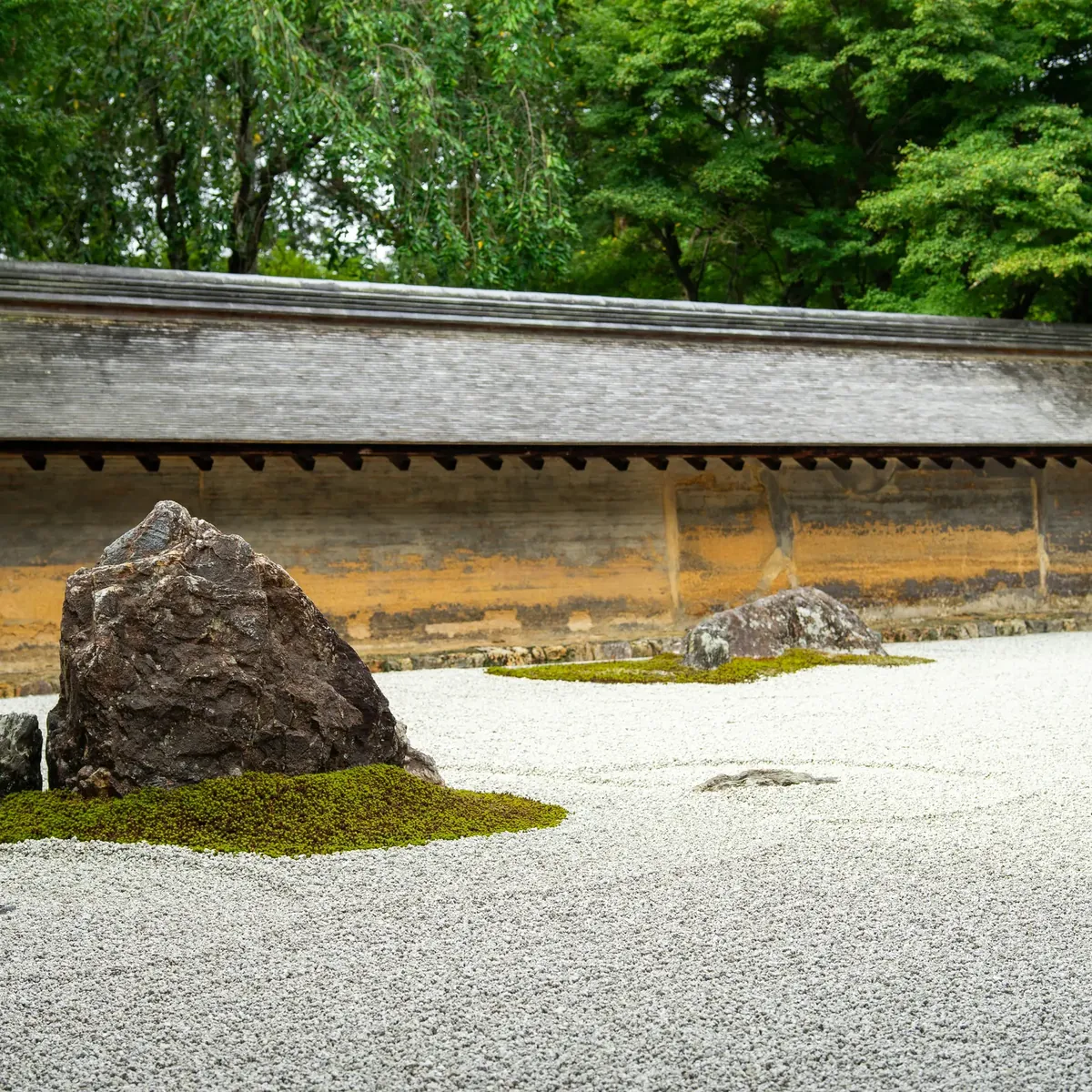 Raked gravel and a moss-ringed rock in the Ryoan-ji rock garden in Kyoto, a garden a private guide helps you read