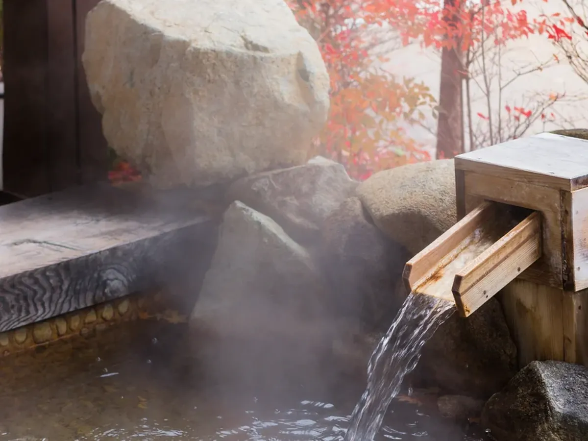 Outdoor onsen rotenburo at a luxury ryokan in Japan with autumn foliage