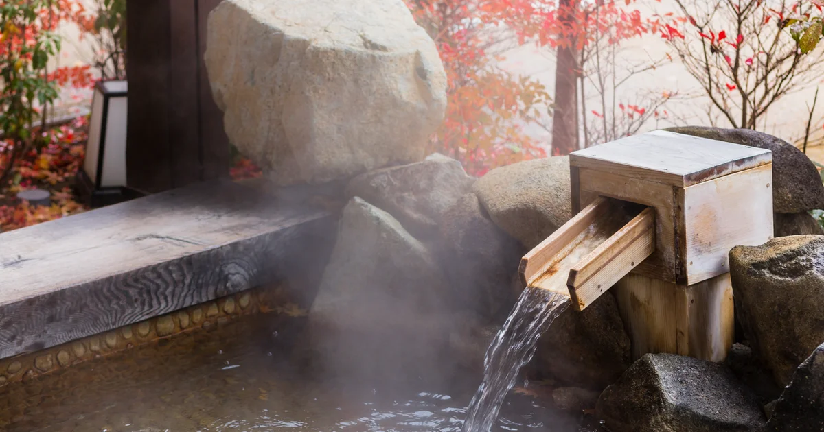 Outdoor onsen rotenburo at a luxury ryokan in Japan with autumn foliage