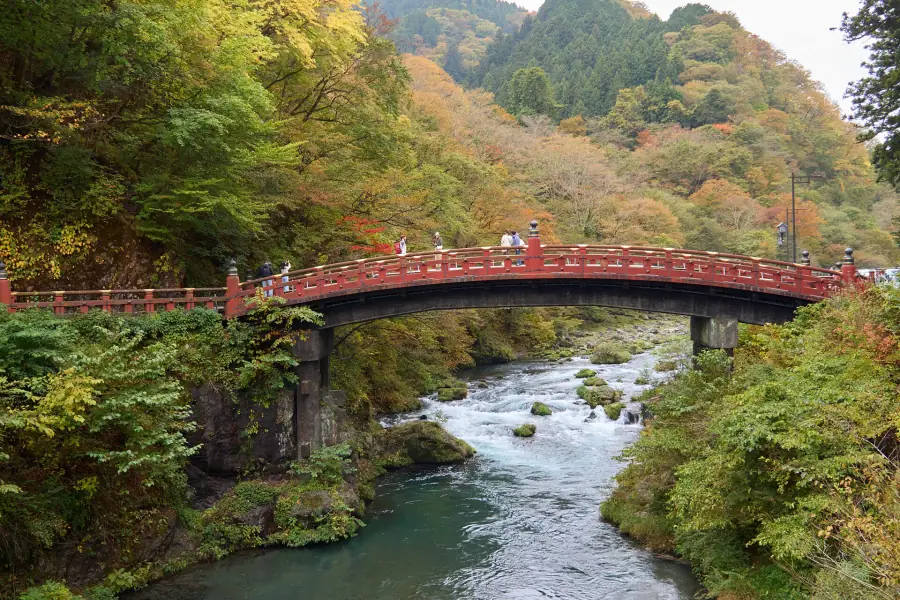The red Shinkyo Bridge over the Daiya River in Nikko, surrounded by early autumn color