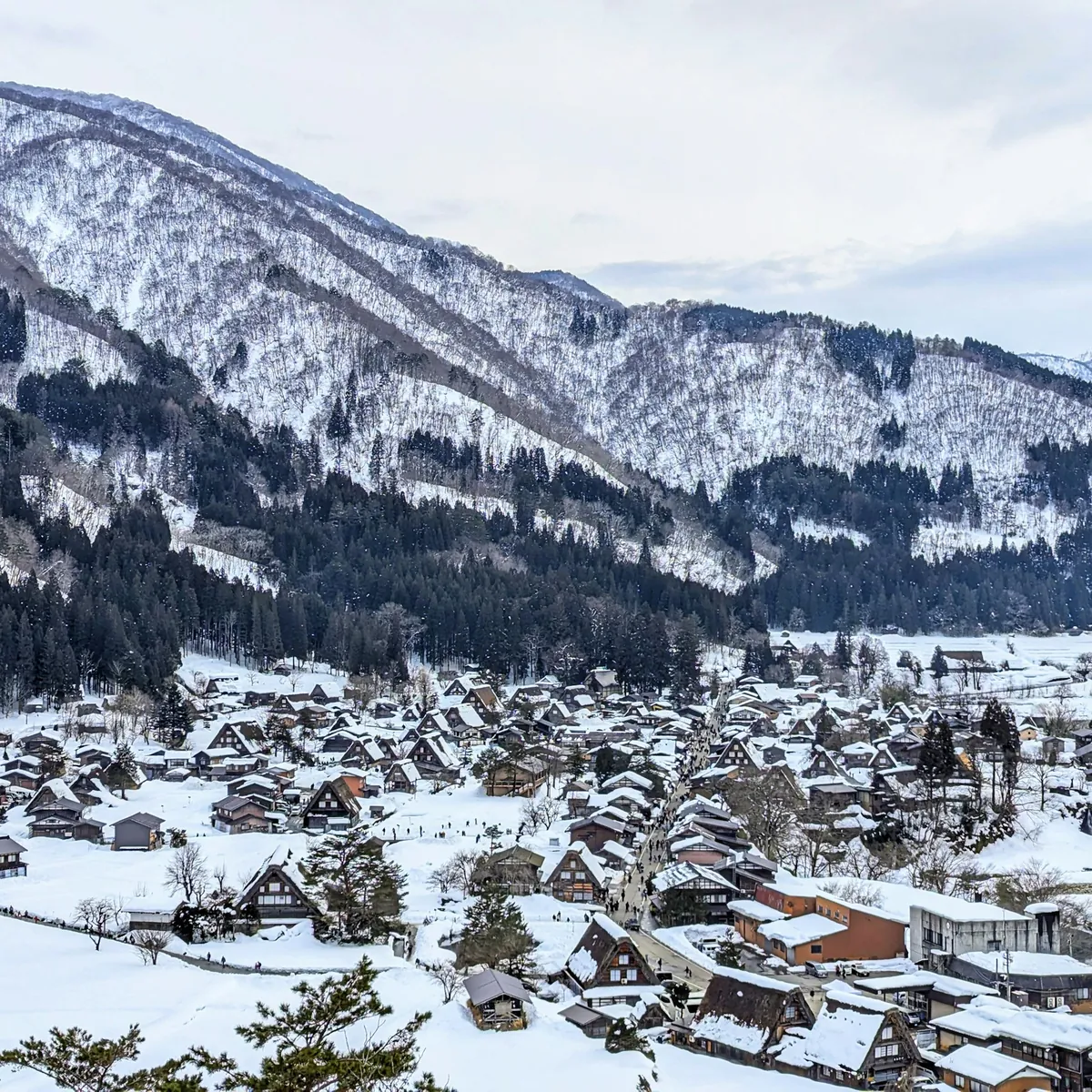Shirakawa-go village under deep snow in winter, gassho-zukuri farmhouses below the mountains, Gifu, Japan