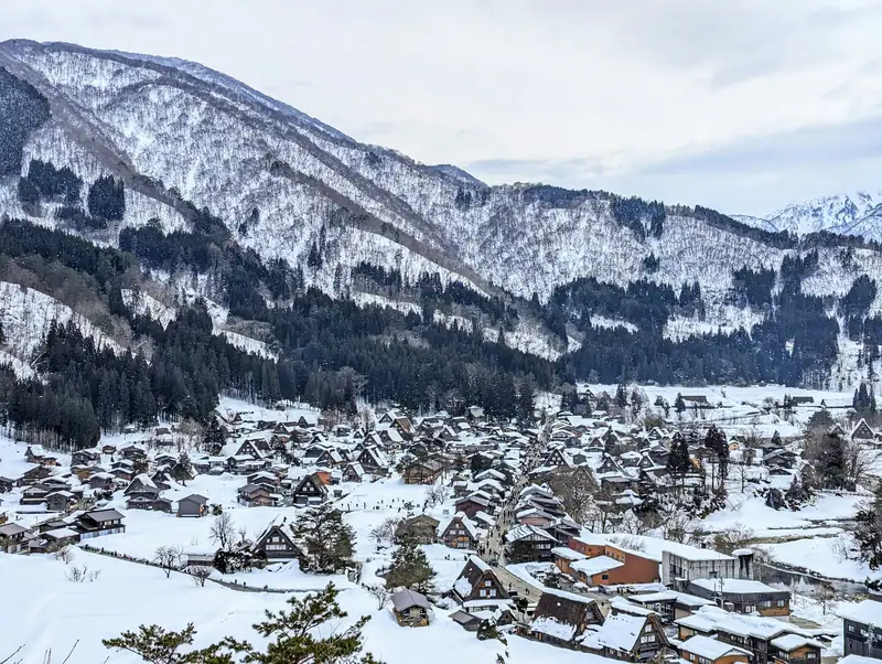 Shirakawa-go village under deep snow in winter, gassho-zukuri farmhouses below the mountains, Gifu, Japan