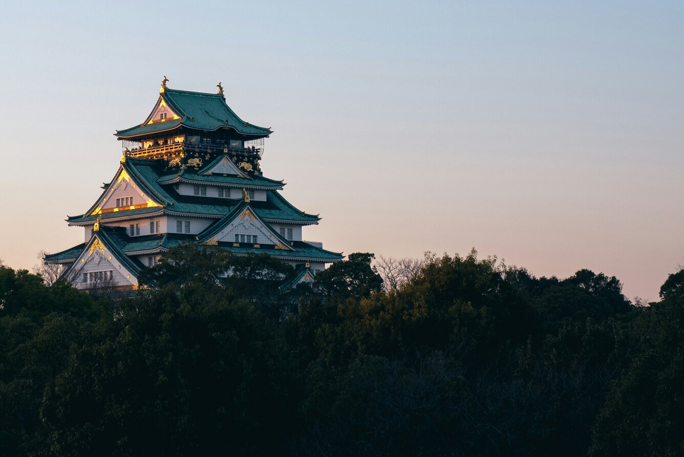 Osaka Castle illuminated at dusk against a gradient sky