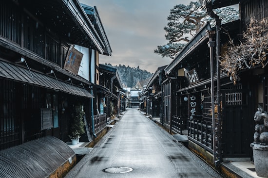 The dark-timbered merchant houses of Takayama's old town under falling snow